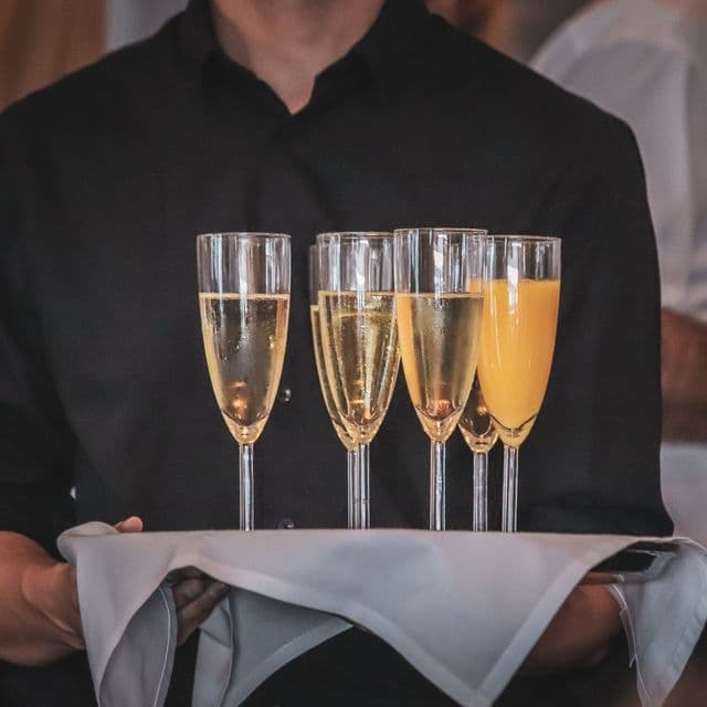 A waiter’s tray of champagne flutes at a dark-tie event