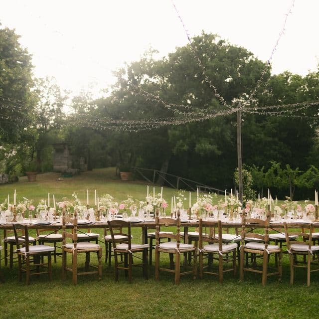 A long garden dinner table with candles at golden hour