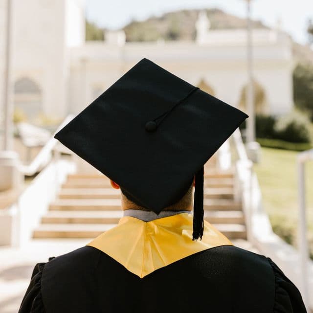 A graduate in cap and gown seen from behind at the ceremony