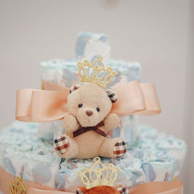 A teddy-bear diaper cake with a peach ribbon