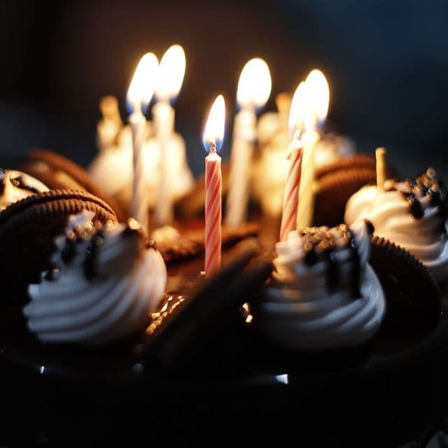 A chocolate birthday cake glowing with candles
