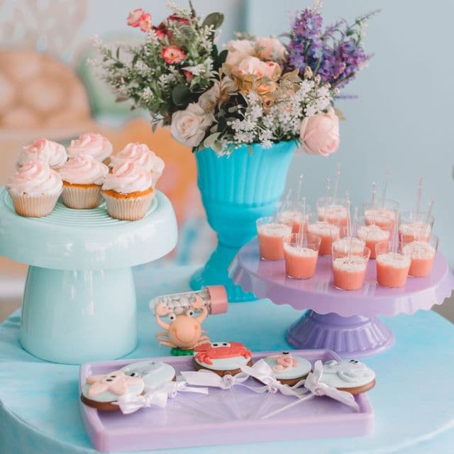 A pastel dessert table with cupcakes and flowers