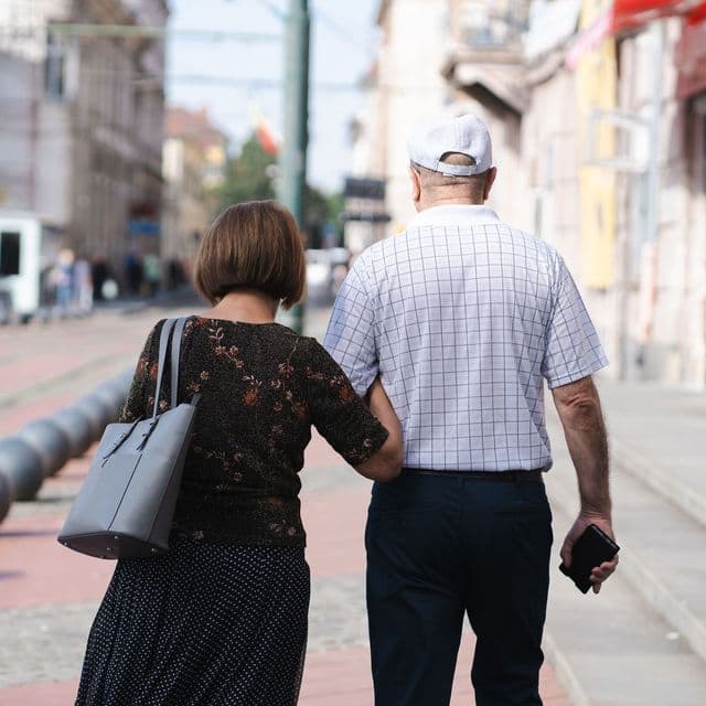 A couple walking away together down a sunlit street