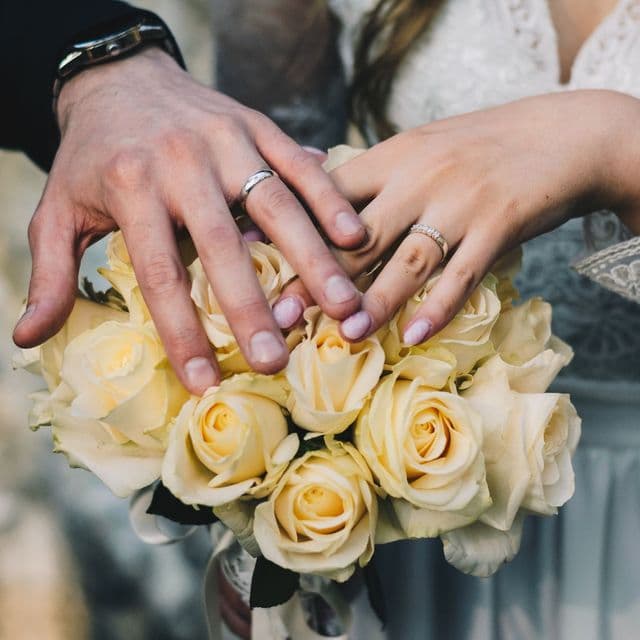 Hands resting on a bouquet of cream roses